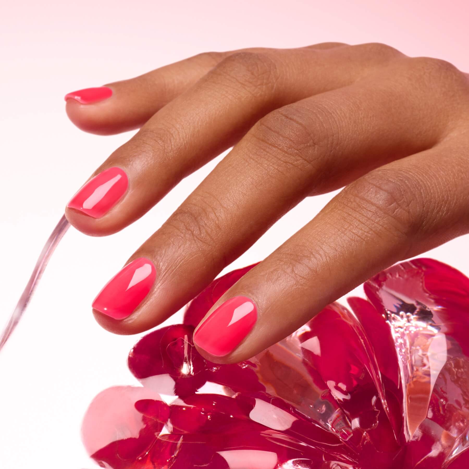 A hand with neatly manicured, ultra-glossy pink nails coated in Manucurist&