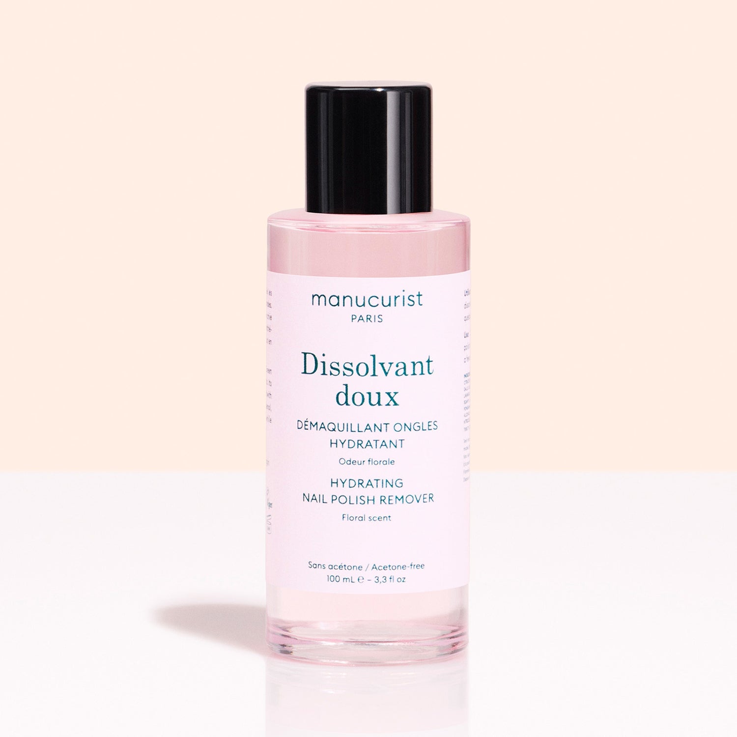 A pink 100 ml bottle of Manucurist Gentle Remover Green™ nail polish remover, plant-based and acetone-free, with a black cap and floral scent, is displayed on a light background.