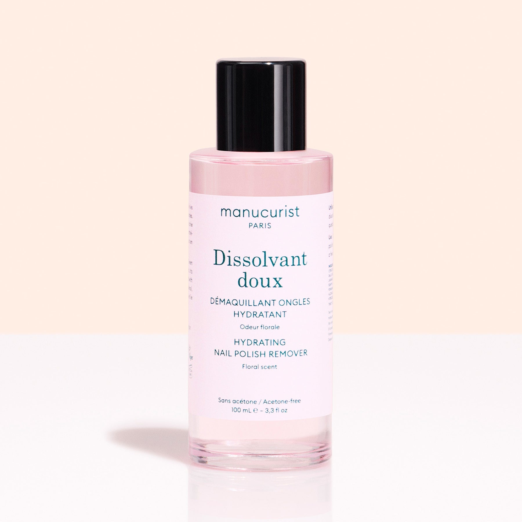 A pink 100 ml bottle of Manucurist Gentle Remover Green™ nail polish remover, plant-based and acetone-free, with a black cap and floral scent, is displayed on a light background.