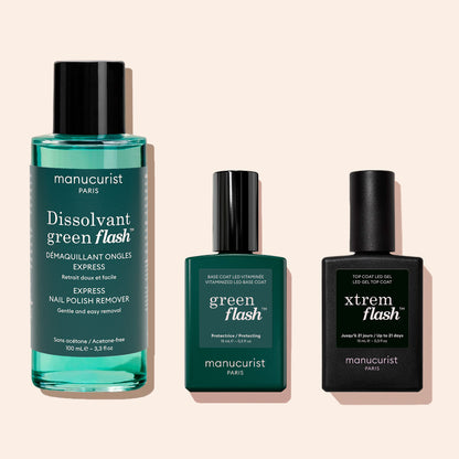 Three Manucurist products: Green Flash™ Gel Polish Remover (100 ml), Green Flash base coat, and Xtrem Flash top coat in green and black packaging, displayed on a beige background.