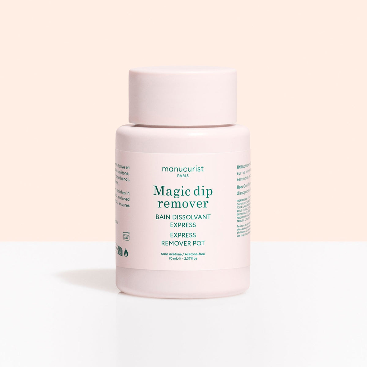 A light pink Manucurist Magic Dip Remover bottle stands against a light peach and white background. The label features product details and icons, emphasizing this acetone-free, travel-friendly express nail polish remover pot.