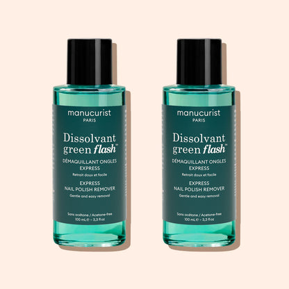 Two bottles of Manucurist Green Flash™ Gel Polish Remover, featuring teal liquid, black caps, and white label text, are displayed against a light beige background.