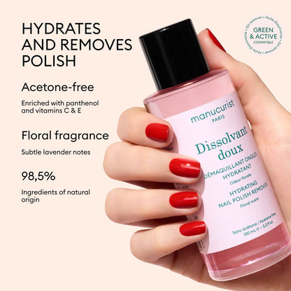 A hand with red-painted nails holds a pink bottle of Manucurist Gentle Remover. This acetone-free nail polish remover is 98.5% natural, floral-scented, and enriched with panthenol plus vitamins C  E to strengthen nails while cleansing.