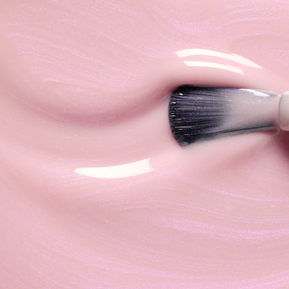 A close-up of the Manucurist Halo brush swirling through glossy pale pink gel, creating smooth, shiny swirls and a reflective surface reminiscent of glazed nail polish.