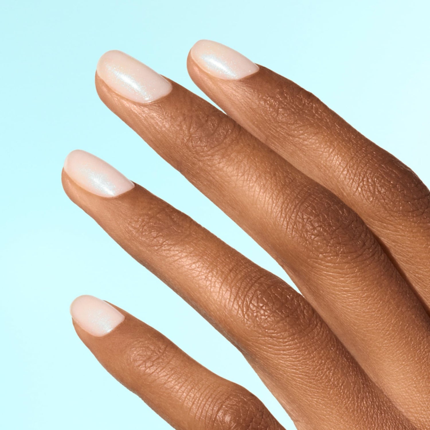 A close-up of a medium-brown hand with four fingers extended, nails neatly manicured and coated in Manucurist&