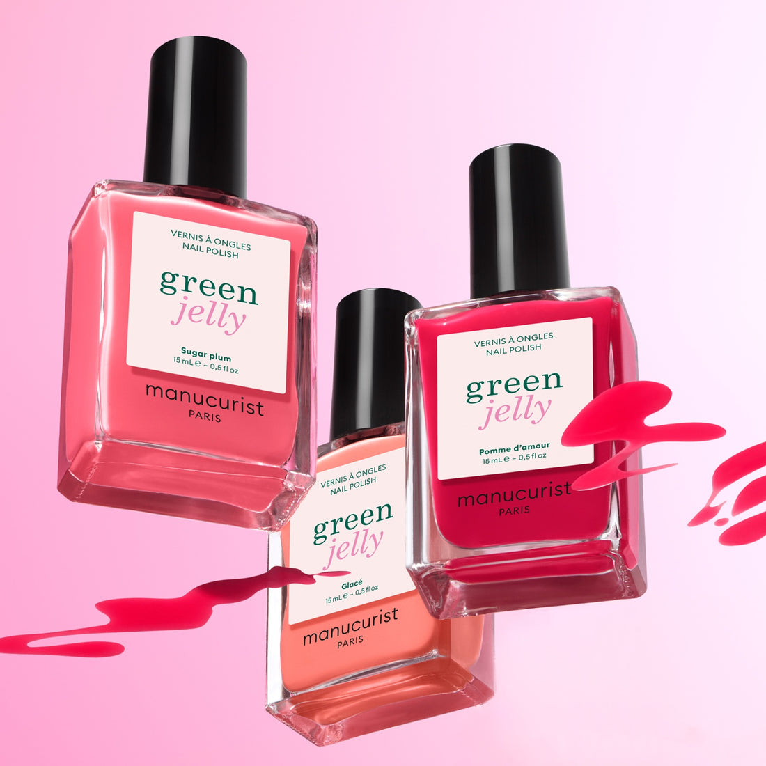 Three bottles from the Manucurist Trio Collections are shown against a pink gradient background, splashed with polish—capturing modern nail trends and vibrant color palettes.
