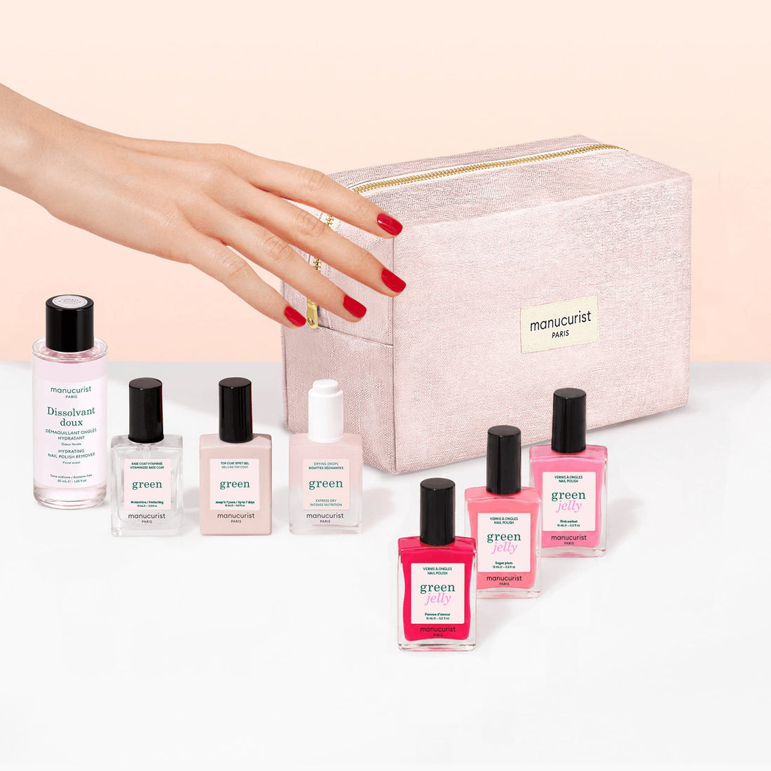 A hand with red nails reaches toward the Manucurist Starter Kit - Jelly Nail Polish, featuring gel-effect polish bottles and a remover, all arranged beside an organic cotton pouch labeled manucurist PARIS on a white surface.