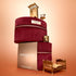 Two red velvet zippered cases from the Green Flash™ Gift Set Holiday by Manucurist are stacked on top of a box labeled “manucurist PARIS,” with miniature golden beds and a chair arranged on and around the cases.