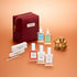 The Manucurist Active™ Starter Gift Set, featuring a burgundy pouch, nail care bottles with droppers, three nail files, and a gold miniature carriage, is beautifully arranged on a peach-colored surface—providing everything you need for a flawless manicure routine and beautiful nails.