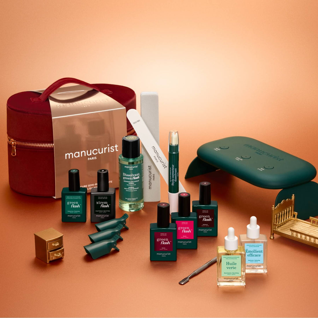 Manucurist Green Flash™ Addict Kit Gift Set featuring a small portable LED lamp, several nail polish bottles, a nail file, a corrective pen, cuticle oil, nail clips, and a red carrying case.