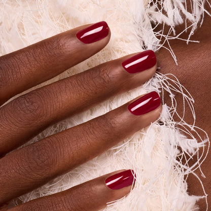 Fingernails painted with a glossy, luminous burgundy Amour gel polish by Manucurist.