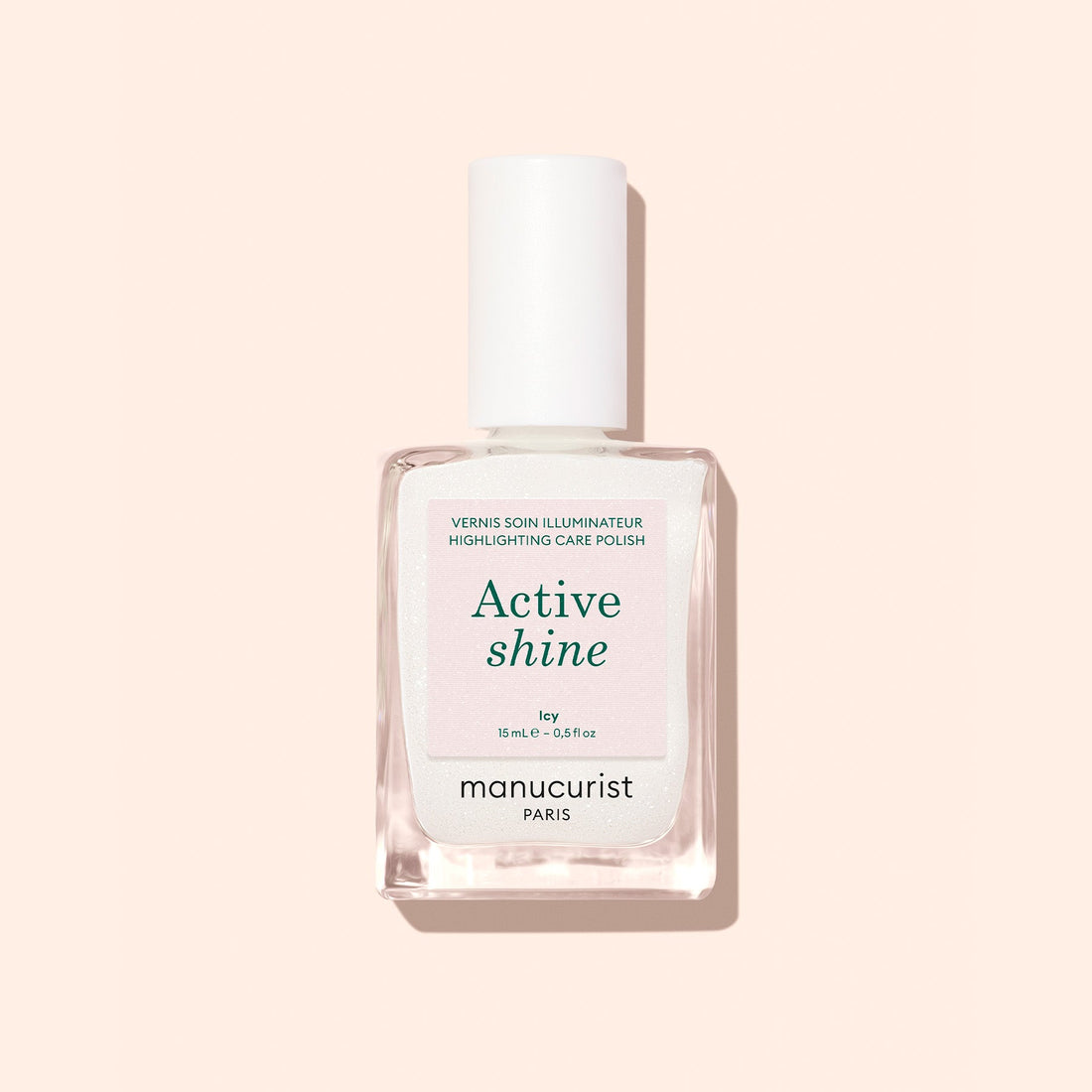 A bottle of Manucurist Active™ Shine Icy nail polish sits on a pale peach background with a subtle shadow, offering the perfect touch for brighter-looking nails and advanced nail care.