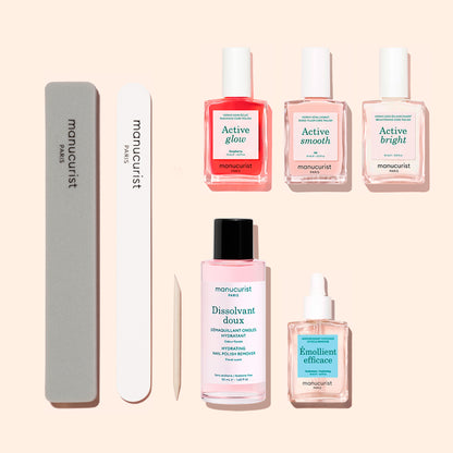 The Active™ Manicure Kit by Manucurist features three nail polishes, nail files, a cuticle remover, a nourishing nail serum, a nail polish remover bottle, and a cuticle oil dropper—all beautifully arranged on a light beige background—making it the perfect all-in-one solution for your complete nail care routine.