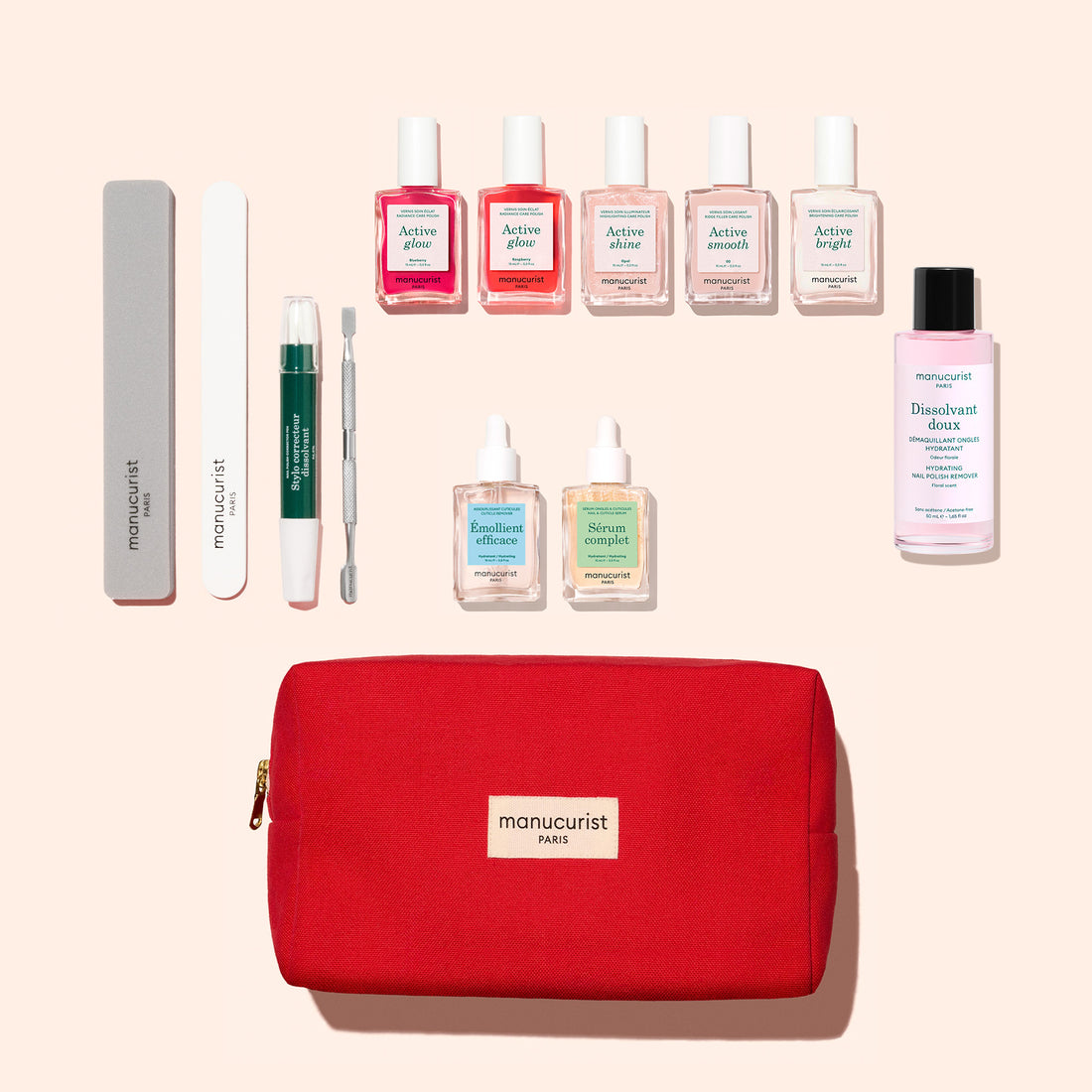 The Manucurist Active™ Super Ultimate Manicure Kit is displayed in a red bag branded with “manucurist”, featuring a complete nail care collection: nail care tools, six bottles of polish, three skincare vials, and a bottle of gentle cuticle remover—all arranged neatly on a beige background for healthy nails.