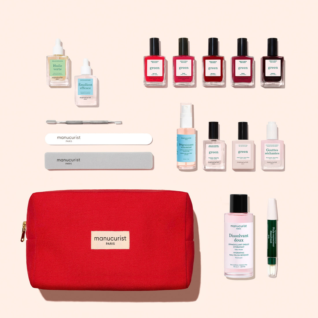 A Super Addict Kit by Manucurist featuring a red zippered pouch and green manicure kit, including various nail polish bottles, a Vitaminised Base Coat, oils, removers, and nail tools arranged on a light background.