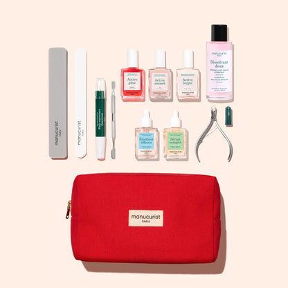 The Manucurist Active™ Ultimate Manicure Kit features a vibrant red pouch filled with essential nail care tools—including files, cuticle remover, nail clippers, treatment bottles, and polish remover—all thoughtfully arranged on a light background to help you achieve beautifully healthy nails.