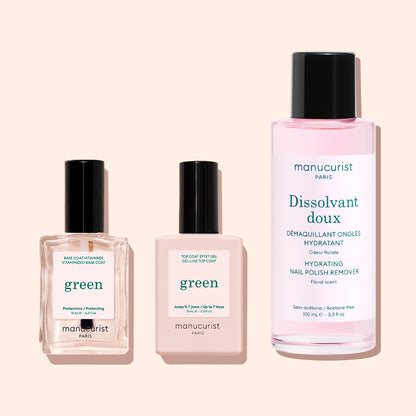 Three manicure products on a light pink background: two square bottles of Manucurist Vitaminised Base Coat Green™ with KeraHCE+ to strengthen nails, plus one larger bottle of pink Manucurist hydrating nail polish remover.