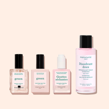 Four Manucurist nail care products, including the Vitaminised Base Coat Green™, with KeraHCE+ to strengthen nails, are lined up on a soft pink background. The tallest bottle on the right is a pink liquid nail polish remover.