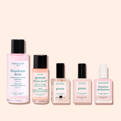 Five Manucurist bottles with black or white caps are lined up on a pale pink background. The labels display the brand along with product names such as Gentle Remover, an acetone-free nail polish remover.