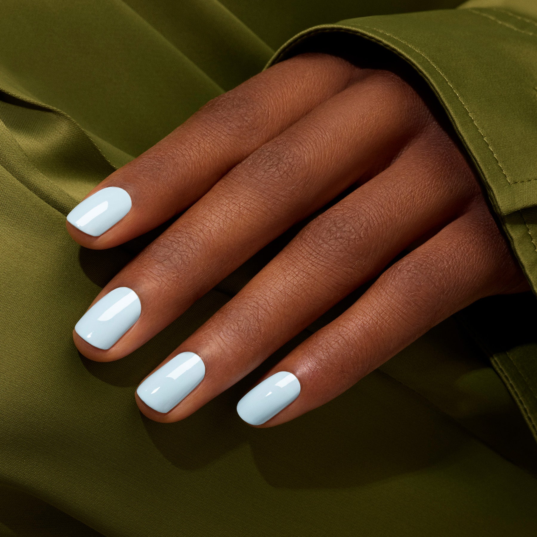 A hand with medium brown skin shows neatly manicured nails painted with Manucurist&