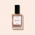 A bottle of Manucurist nail polish in the shade Sandstone is displayed on a light beige surface, with its shadow cast beside it.