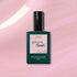 A bottle of Halo gel polish by Manucurist sits on a shimmery pink surface. The dark green bottle features a pink label with the shade name Halo.
