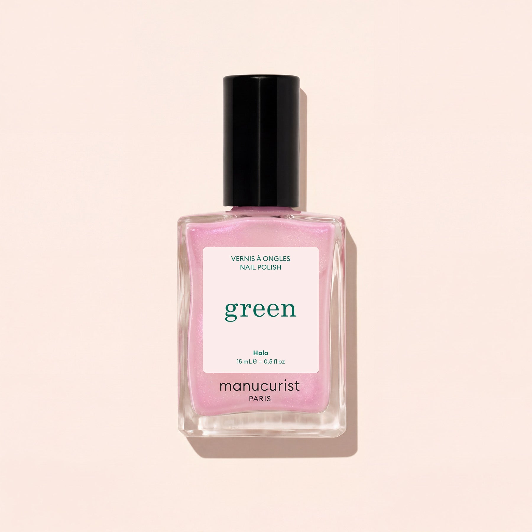Manucurist’s Green glazed nail polish in the light pink shade “Halo,” shown with a black cap against a pale pink background.