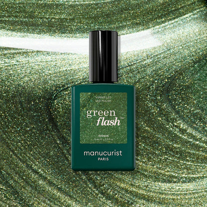 A bottle of Manucurist Groove Green Flash gel in a pearly green shade is displayed against a swirling, sparkling green background that perfectly matches the color of the Groove Green Flash gel.