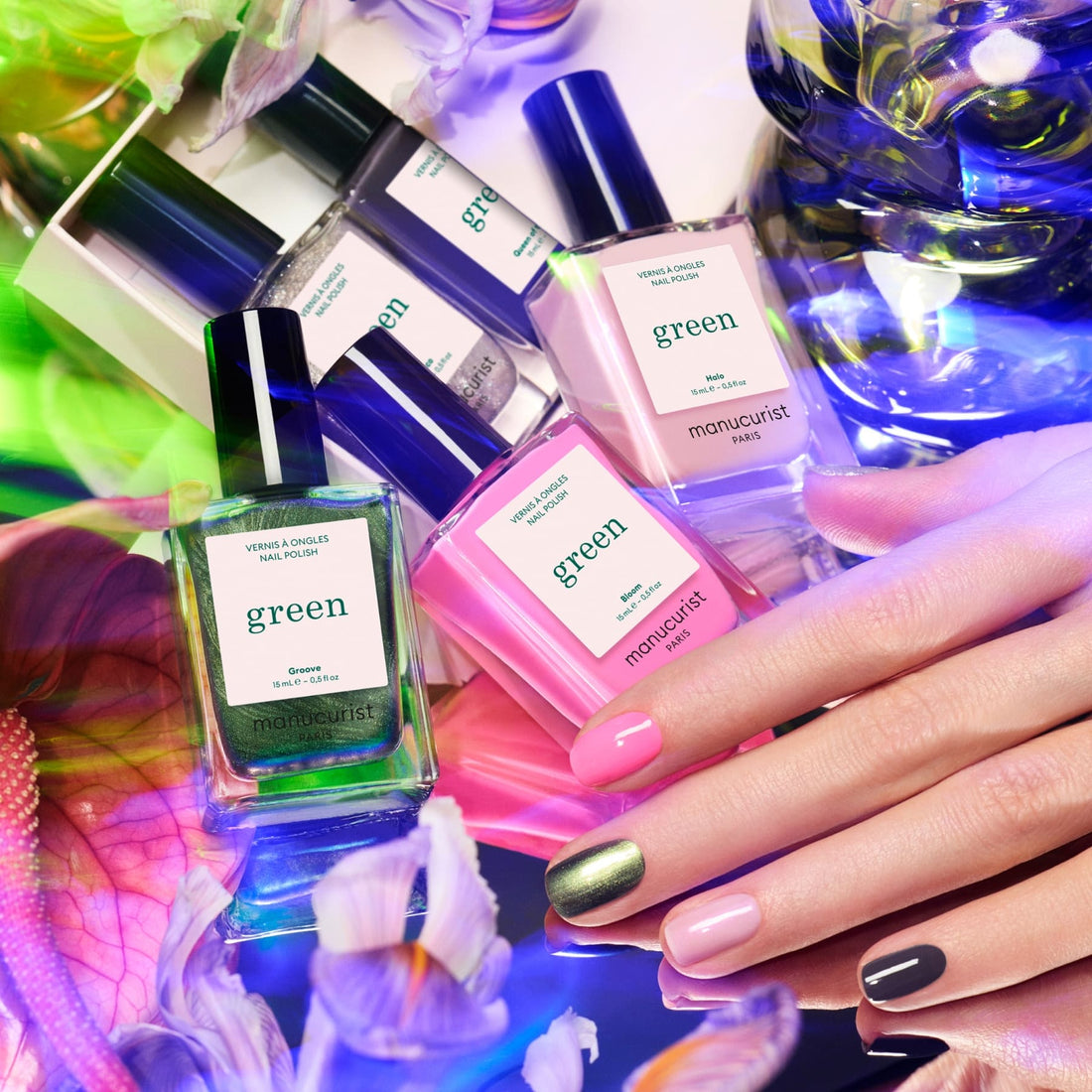 Bottles from the Manucurist Rainbow Collections are displayed among vibrant flowers, while a hand with pink, nude, and metallic green nails highlights creative nail art inspired by Manucurist’s curated colour palettes.