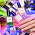 Bottles from the Manucurist Rainbow Collections are displayed among vibrant flowers, while a hand with pink, nude, and metallic green nails highlights creative nail art inspired by Manucurist’s curated colour palettes.