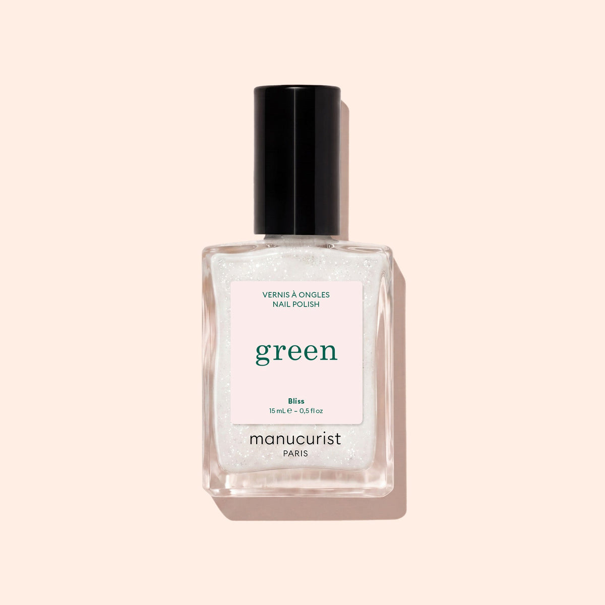 A clear glass bottle of Manucurist nail polish in the shade Bliss, featuring a black cap, is shown against a light beige background.