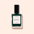 A bottle of Manucurist Emerald nail polish, a deep forest green shade inspired by gemstones, from the Green™ range with a black cap, displayed against a light beige background.