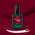 A bottle of Manucurist Amour gel polish rests on a deep burgundy background, with a swipe of luminous burgundy nail color displayed beneath it.