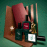 Three green bottles labeled Customisable Trio Green Flash by Manucurist are arranged with a gold figure, a small tea set, and striped and maroon props on a green background—perfect inspiration to create your own trio with their acetone-free gel polish remover for a complete manicure experience.