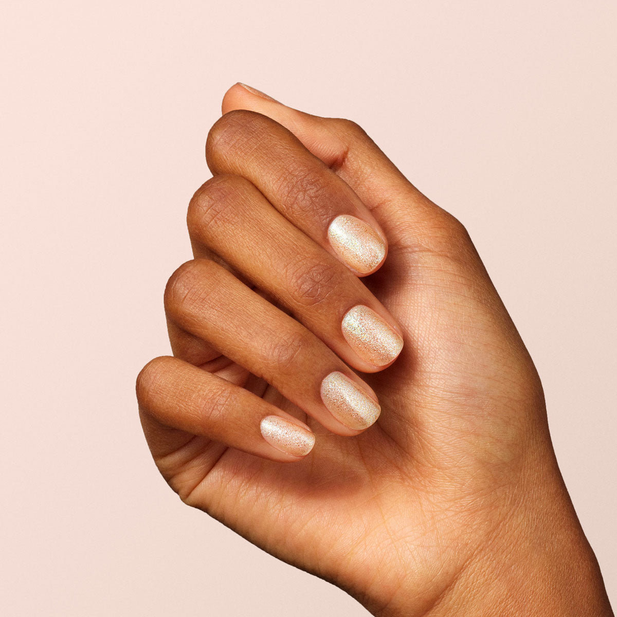 A hand with medium brown skin shows neatly manicured nails painted with Manucurist&