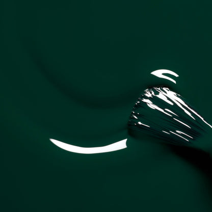 A close-up of a metallic whisk stirring Manucurist’s Emerald—a thick, deep forest green nail polish—captures reflections of light as bright white highlights glint across the surface, evoking the luxurious shimmer of this gemstone-inspired shade.