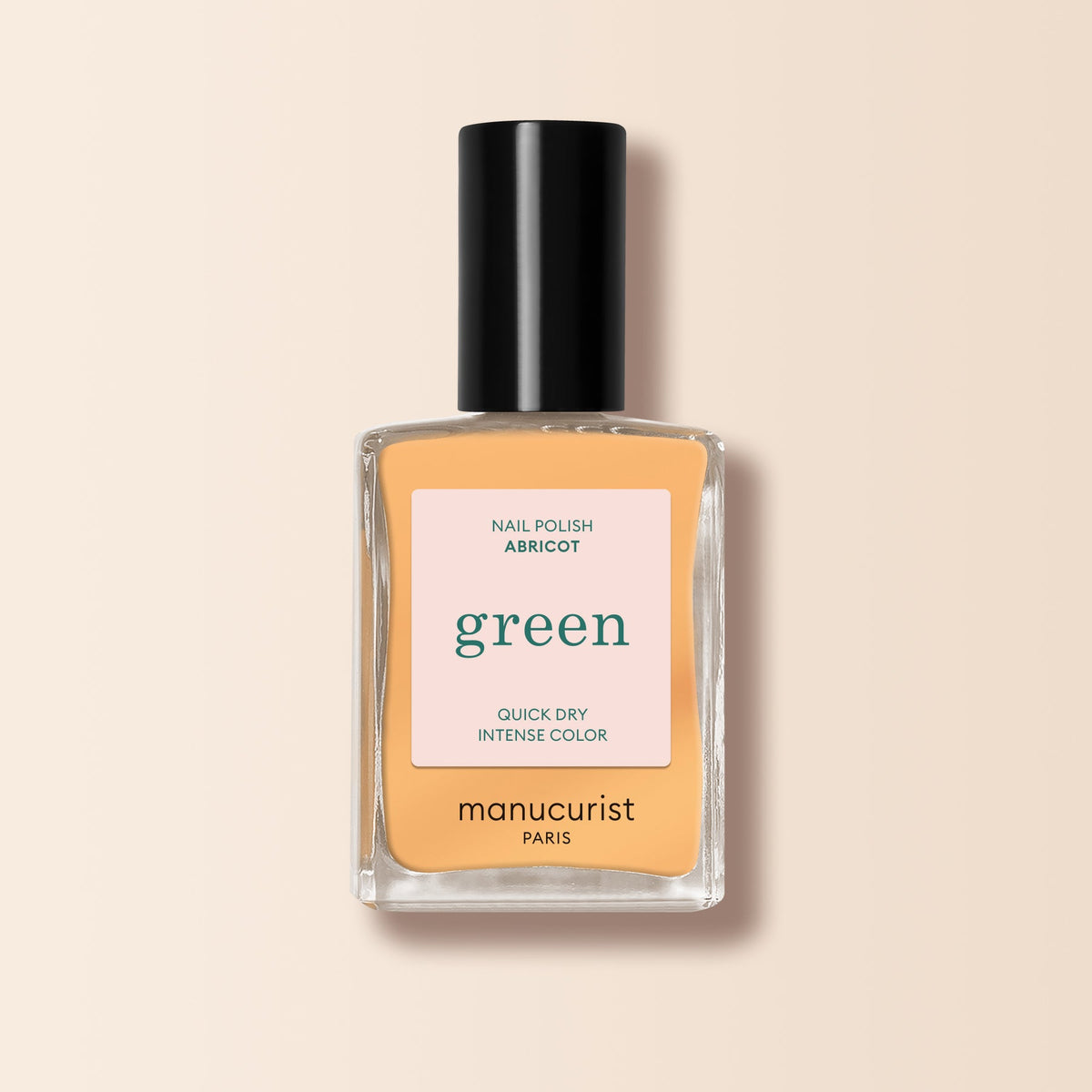 A bottle of Manucurist Abricot nail polish from the Green range in a peachy apricot shade, with a black cap, shown against a light beige background.