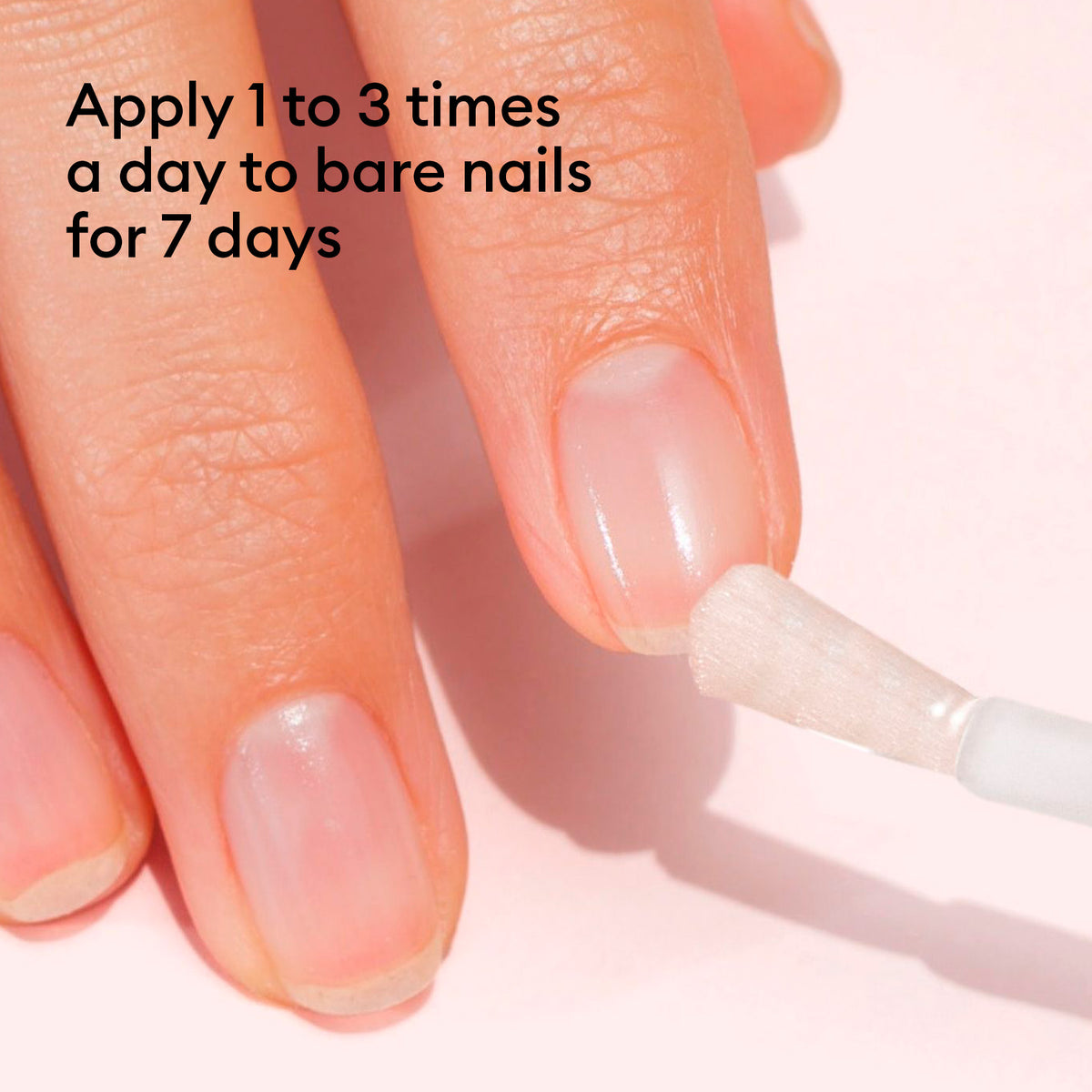 A hand applies Manucurist Nail Strengthening Serum to fingernails with a brush. Text: Apply 1–3 times daily to bare nails for 7 days. A light pink background highlights gentle care for damaged nails.