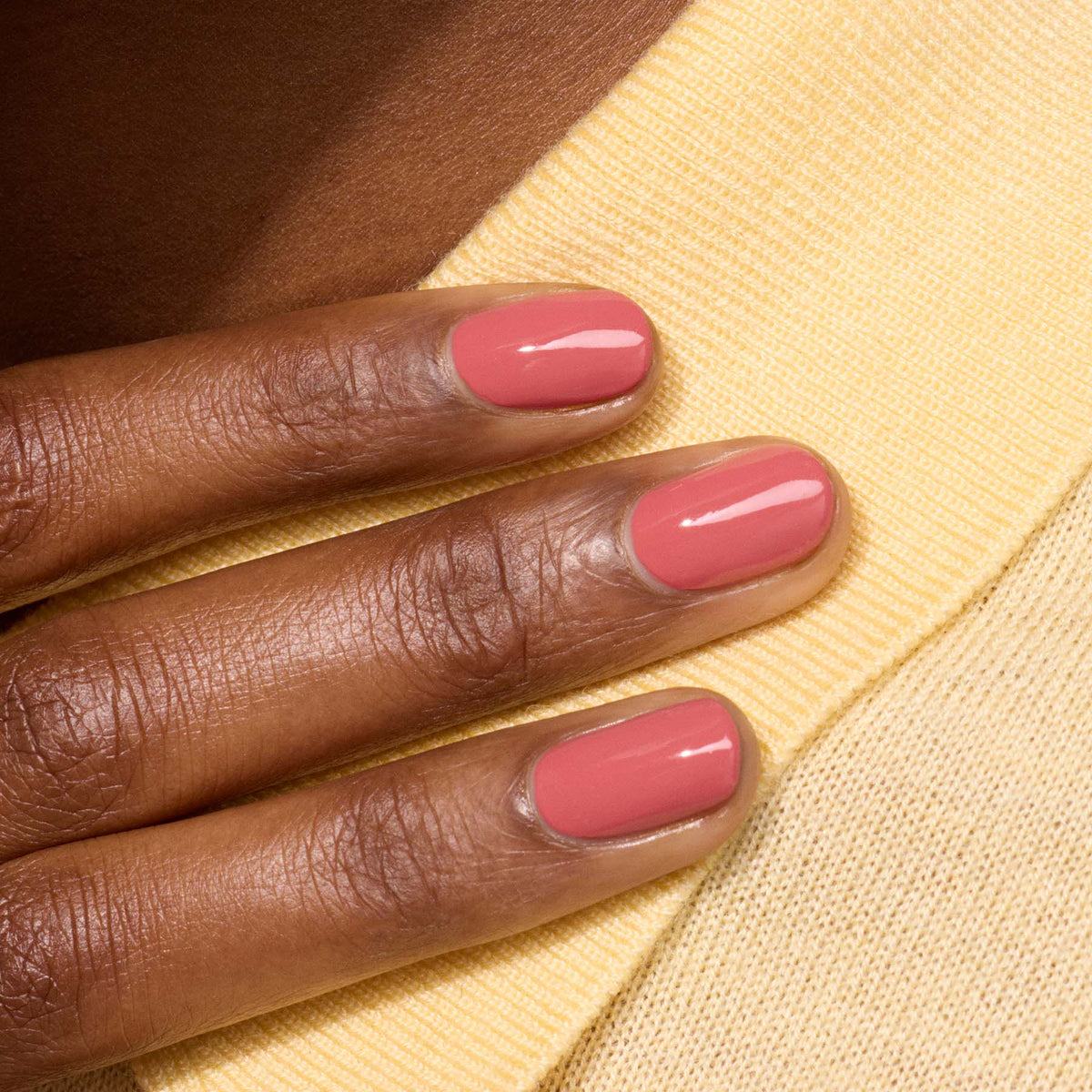 A close-up of a hand with medium brown skin and neatly manicured nails painted in Manucurist&