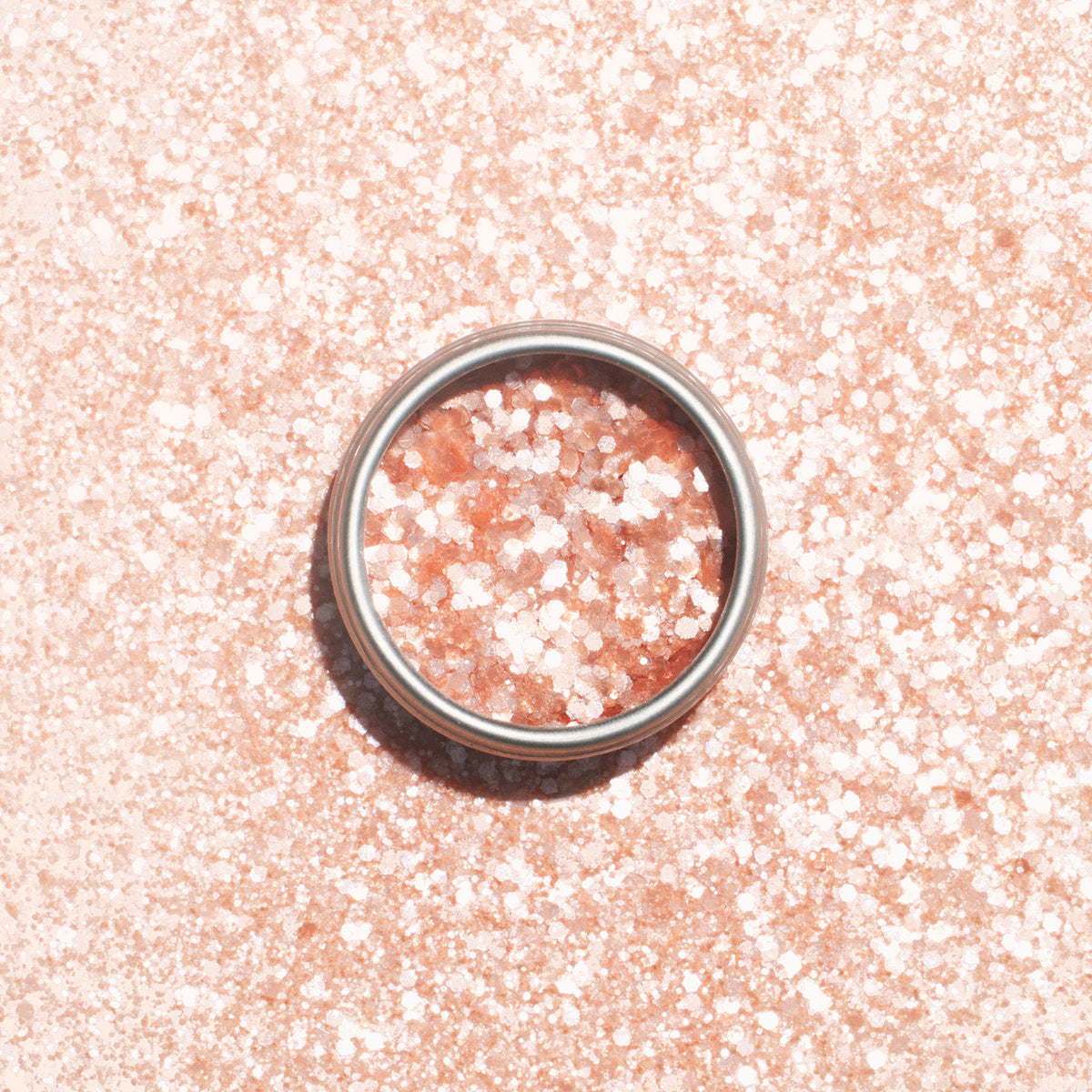 A metal ring sits on a sparkling pink surface dusted with Manucurist&
