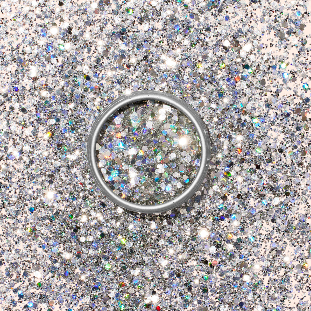 A silver ring rests on a shimmering bed of Manucurist Holo biodegradable glitter, creating a festive and sparkling background.