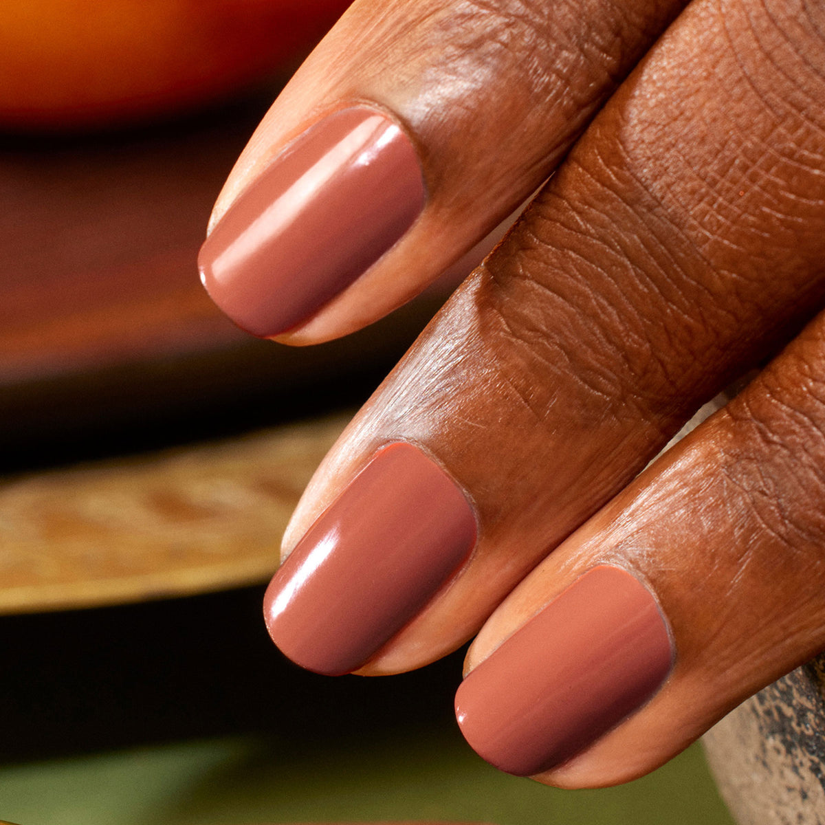 A close-up of a hand with medium brown skin shows neatly manicured nails painted with Manucurist’s "Oriental Vibe," a glossy mauve-pink polish from the Autumn 23 collection.