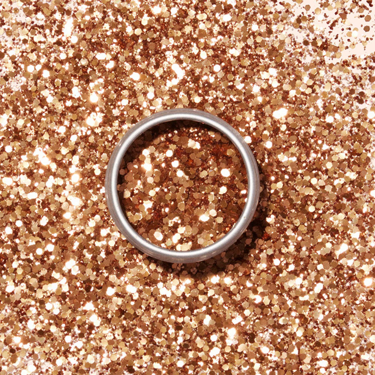A silver ring rests on a surface dusted with Manucurist Biodegradable Glitter, an eco-friendly sparkling product.