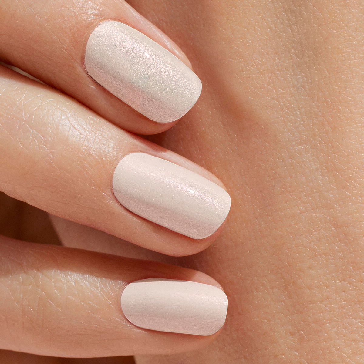 A close-up of a hand with glossy, pale pink manicured nails, featuring smooth skin and an ultra-glowy finish achieved using The One  Only Duo by Manucurist.