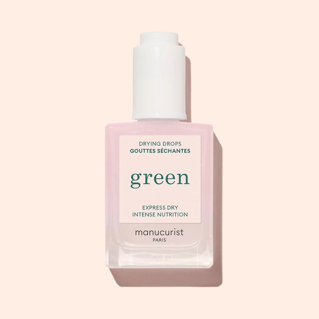 A bottle of Manucurist Drying Drops, a nail-nourishing formula with a pink-tinted liquid and white dropper cap, is shown on a light beige background.