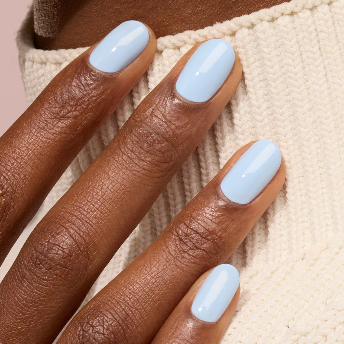 A close-up of a hand with medium brown skin and neatly manicured nails painted in Manucurist&