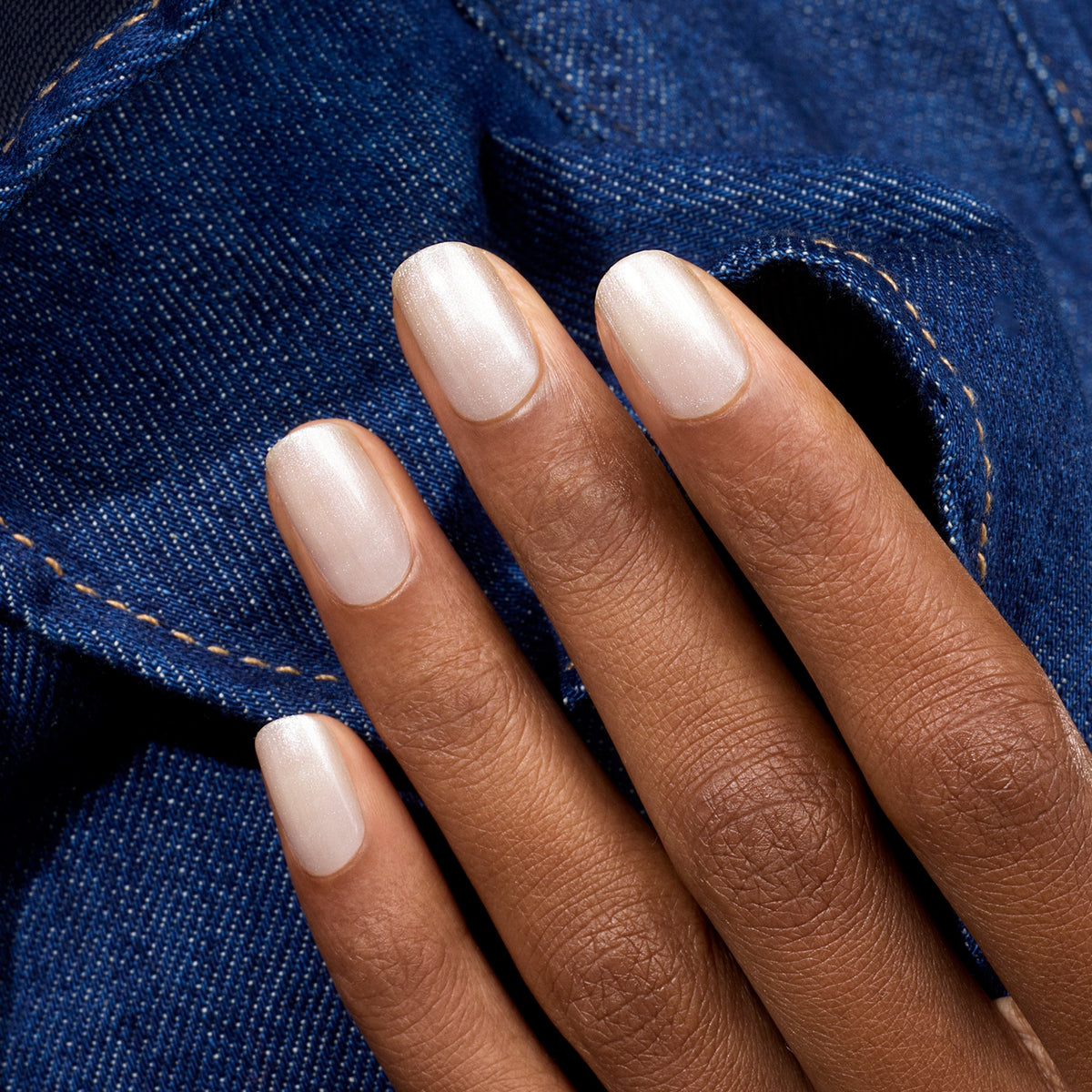 A hand with medium brown skin and neatly manicured nails painted with Manucurist&