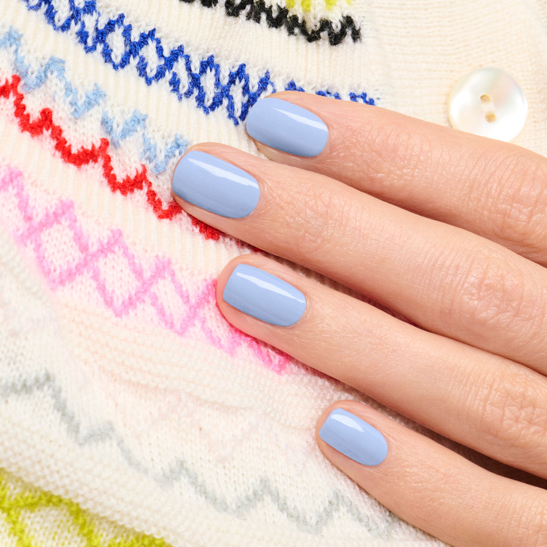 A hand with short, neatly manicured nails painted in Manucurist&