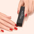 A person holds a black Manucurist Flash Removal Block above fingers with red painted nails.