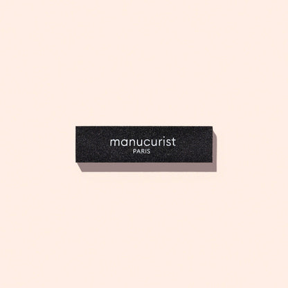 Rectangular black Manucurist Flash Removal Block nail buffer with the brand name printed in white.